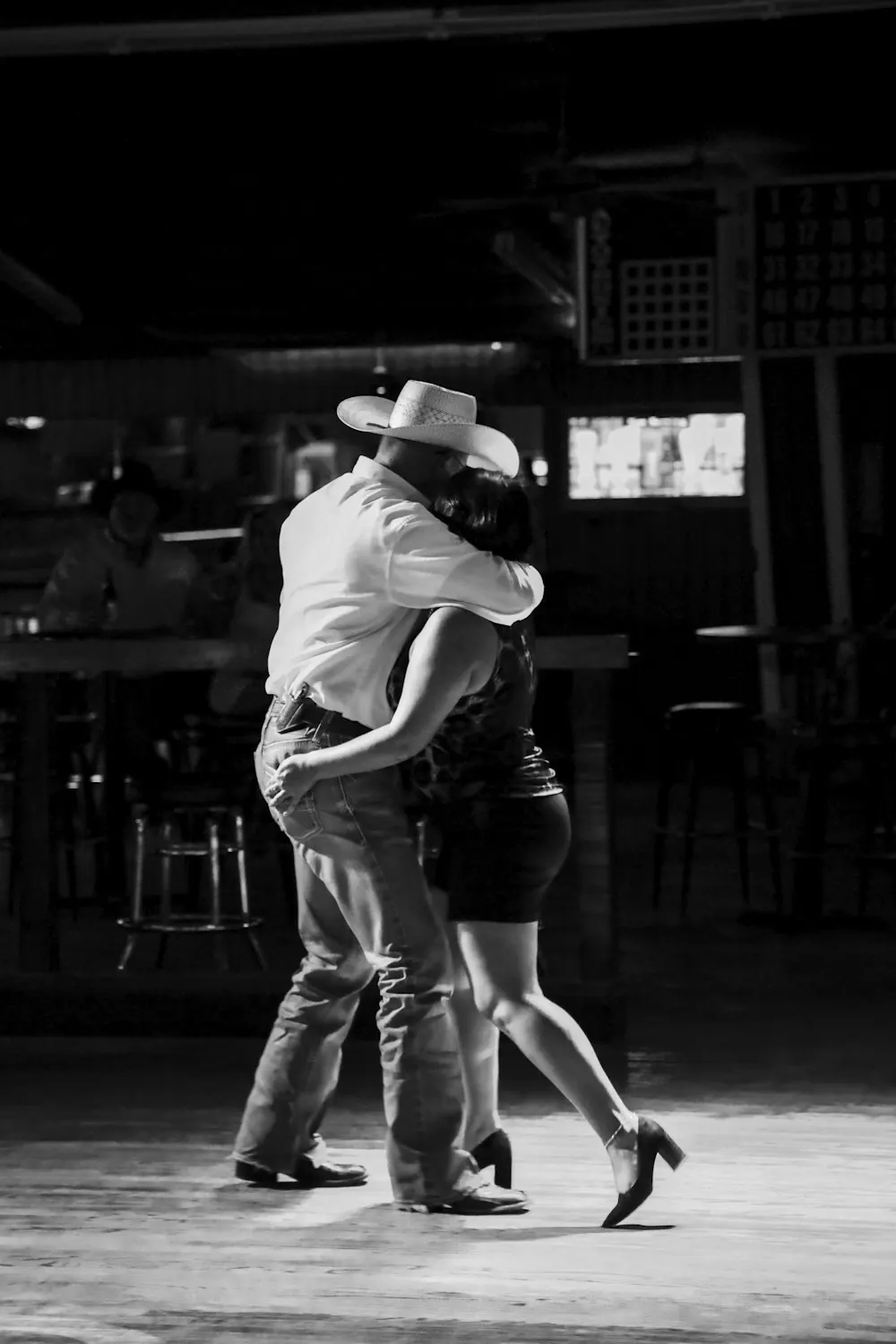 Un couple en chapeau de cowboy qui danse dans un bar