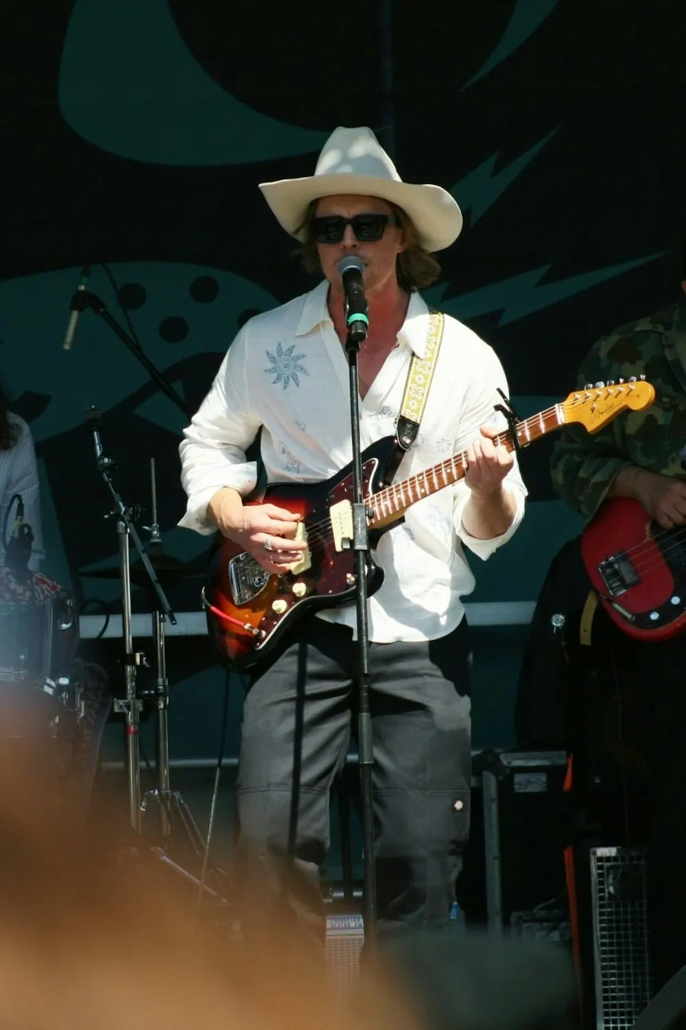 Un chanteur en chapeau de cowboy joue de la guitare électrique sur scène